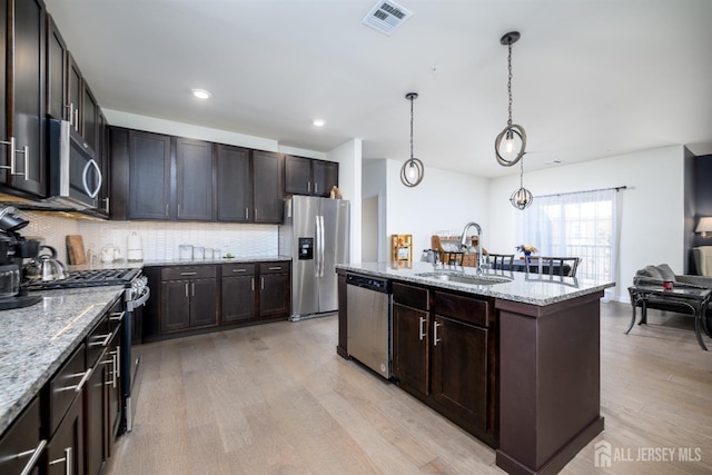 kitchen with pendant lighting, stainless steel appliances, light stone countertops, and sink