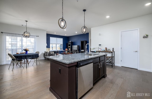 kitchen featuring sink, hanging light fixtures, a center island with sink, light wood-type flooring, and dishwasher