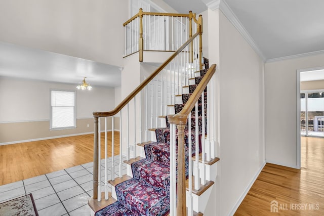 stairs with baseboards, ornamental molding, a chandelier, and wood finished floors