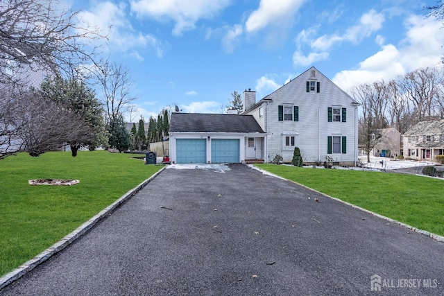 view of front facade with a front yard, driveway, a chimney, and an attached garage