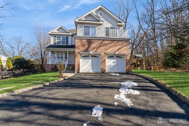 view of front of house featuring brick siding, a balcony, aphalt driveway, an attached garage, and a front yard