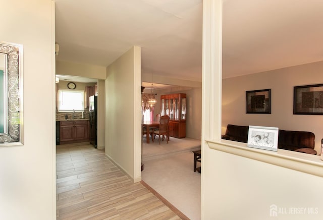 71 S Sagamore Ave, Edison, NJ 08820 - hallway featuring a sink, a chandelier, light wood-style floors, and baseboards
