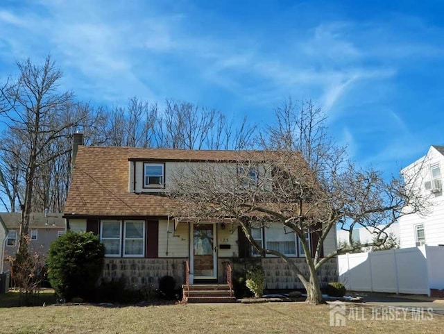 view of front facade with roof with shingles, a chimney, and fence