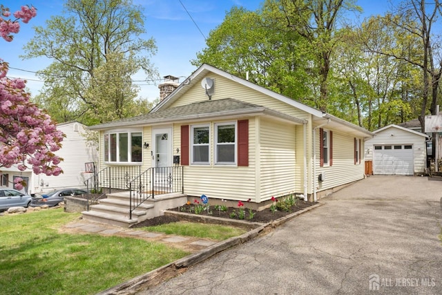 9 Hatakawana Ter, Mount Olive, NJ 07828 - view of front of house with an outbuilding, asphalt driveway, a detached garage, a chimney, and a front lawn