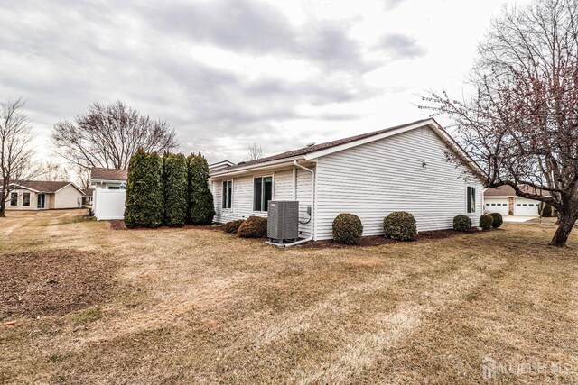 view of side of home featuring a garage, central AC unit, and a lawn