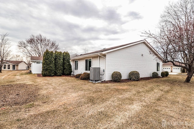 view of side of property with a lawn, central air condition unit, and a garage