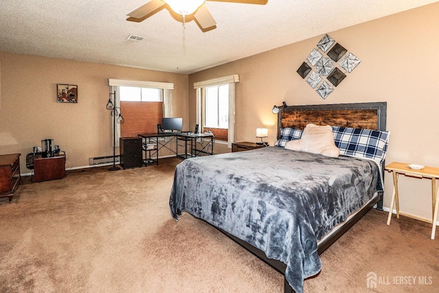 carpeted bedroom with visible vents, baseboard heating, ceiling fan, a textured ceiling, and baseboards