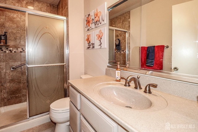 bathroom with toilet, vanity, and a stall shower