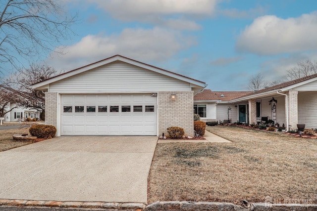 single story home with driveway, a front yard, a garage, and brick siding