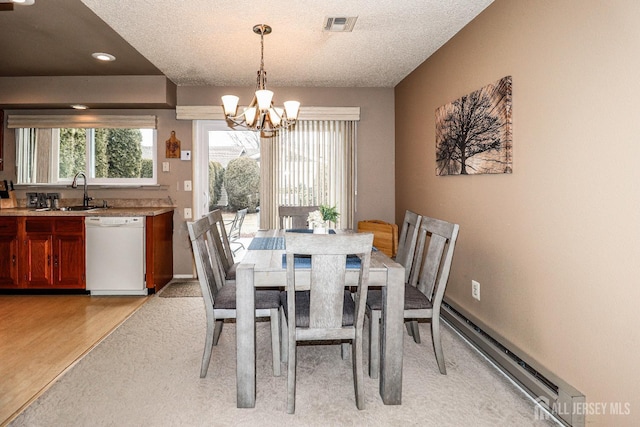 dining space with an inviting chandelier, a wealth of natural light, visible vents, and a baseboard heating unit