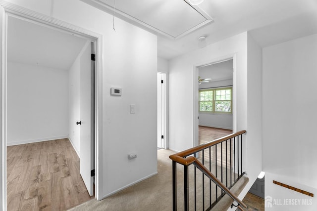 hall with attic access, wood finished floors, an upstairs landing, and baseboards