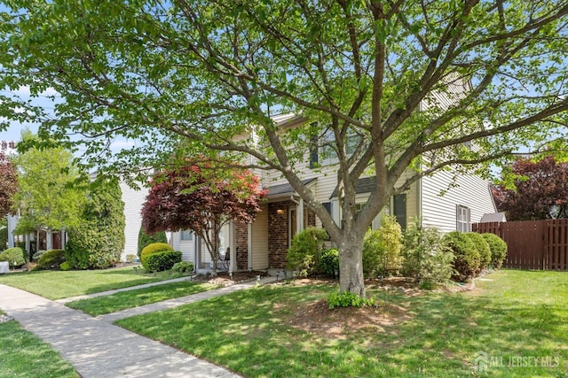 view of property hidden behind natural elements with fence and a front yard