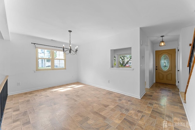 entrance foyer with a chandelier and baseboards