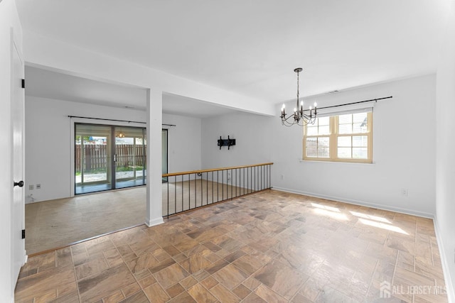 empty room featuring baseboards and a notable chandelier