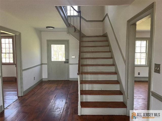 stairs featuring a baseboard heating unit, wood-type flooring, and baseboards