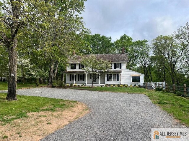 colonial house featuring covered porch and a front yard