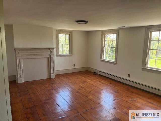 empty room featuring baseboards, baseboard heating, and hardwood / wood-style floors