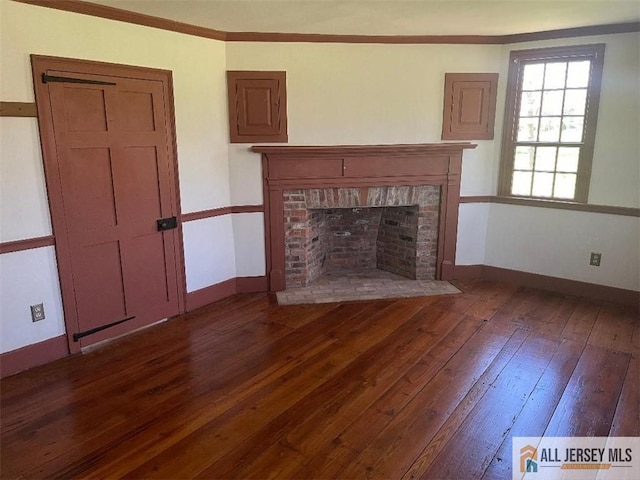 unfurnished living room featuring crown molding, dark wood-type flooring, a fireplace, and baseboards