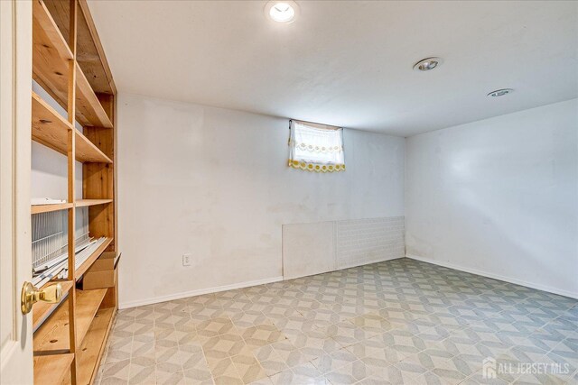 basement with baseboards, light flooring, recessed lighting, and built in features