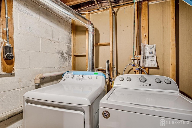 clothes washing area with separate washer and dryer and concrete block wall