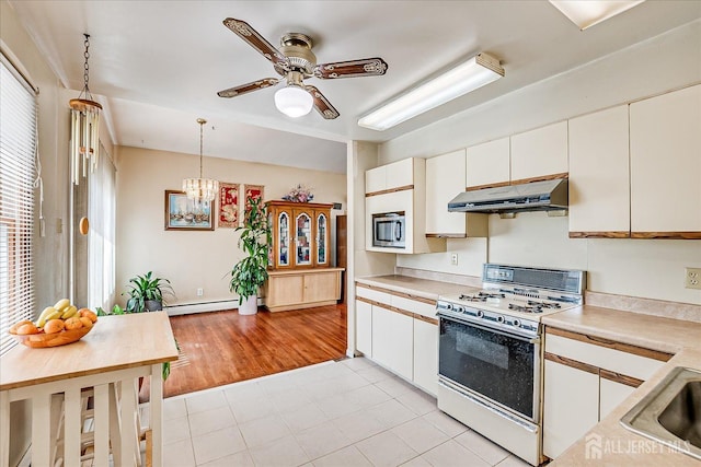 kitchen with gas range gas stove, under cabinet range hood, light countertops, and ceiling fan