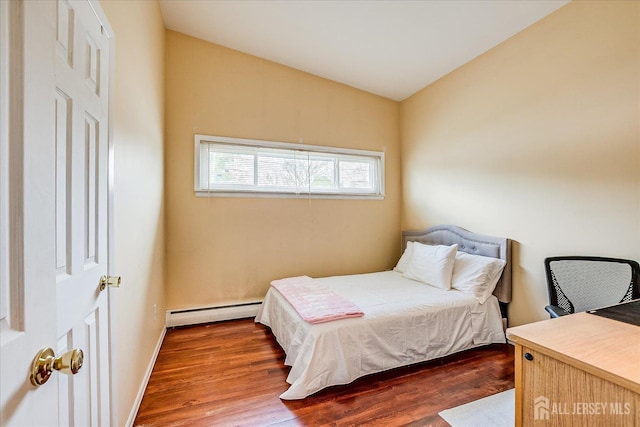 bedroom with baseboard heating, wood finished floors, baseboards, and vaulted ceiling