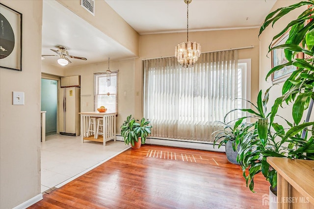 doorway to outside with a baseboard radiator, a chandelier, ceiling fan, wood finished floors, and baseboards