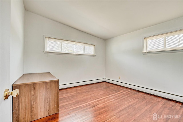 unfurnished room featuring vaulted ceiling, wood finished floors, and a baseboard radiator