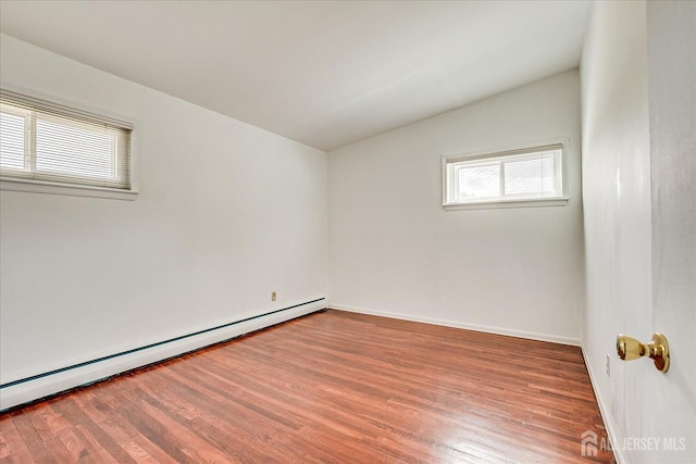 empty room featuring a baseboard radiator, wood finished floors, vaulted ceiling, and baseboards