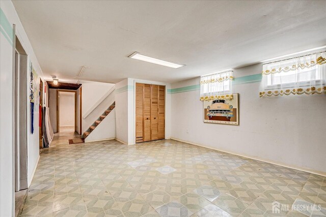 basement with light flooring and stairway