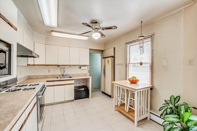 kitchen with gas range oven, under cabinet range hood, freestanding refrigerator, a sink, and light countertops