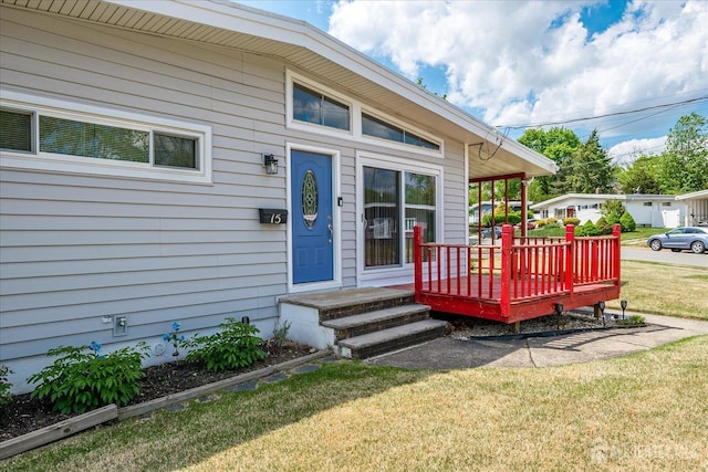 doorway to property featuring a lawn and a deck