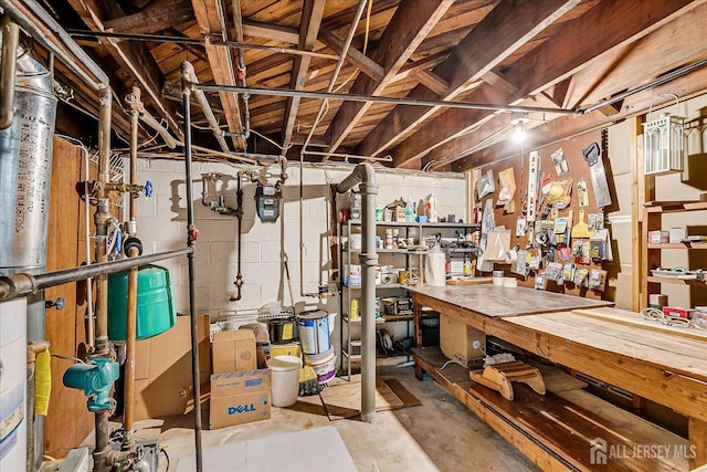 unfinished below grade area featuring a workshop area, concrete block wall, and gas meter
