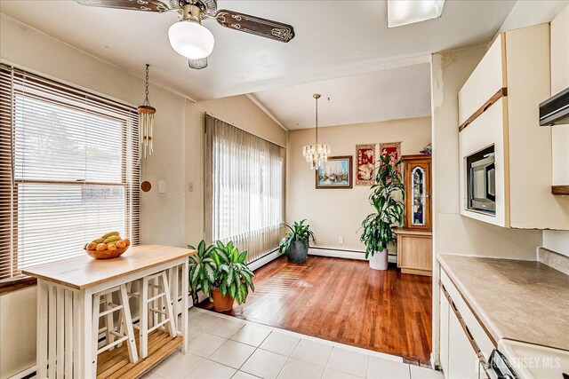 dining room with ceiling fan, light tile patterned floors, lofted ceiling, and a chandelier