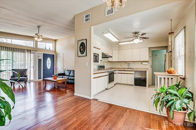 kitchen with gas range gas stove, ceiling fan, under cabinet range hood, and light countertops