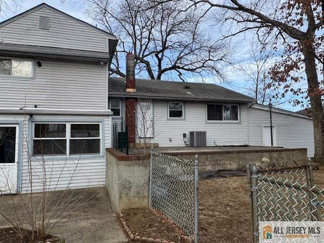 back of property featuring central AC unit, fence, and a gate