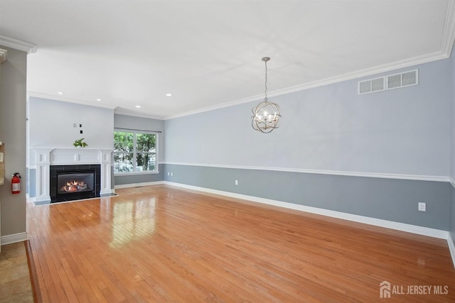 unfurnished living room with baseboards, light wood-style floors, a fireplace with flush hearth, a chandelier, and crown molding