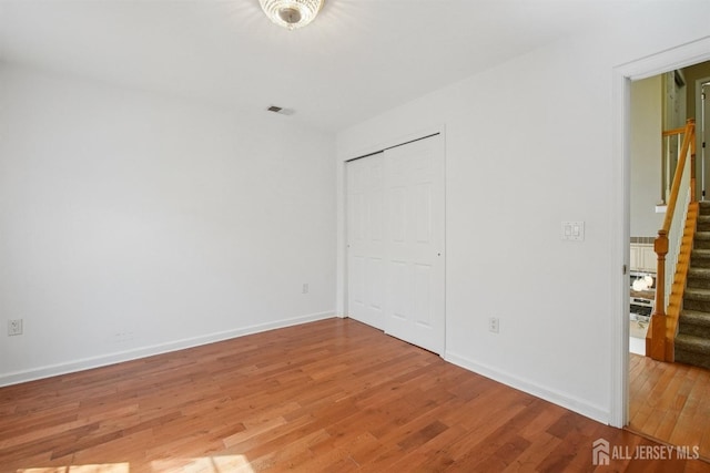 unfurnished bedroom with light wood finished floors, baseboards, and a closet