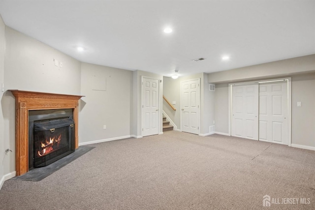 finished basement with a fireplace with flush hearth, baseboards, recessed lighting, carpet, and stairway