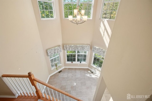 stairs with a towering ceiling, a chandelier, and baseboards