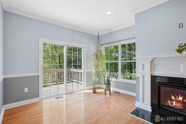 living room with baseboards, a tiled fireplace, hardwood / wood-style floors, ornamental molding, and recessed lighting
