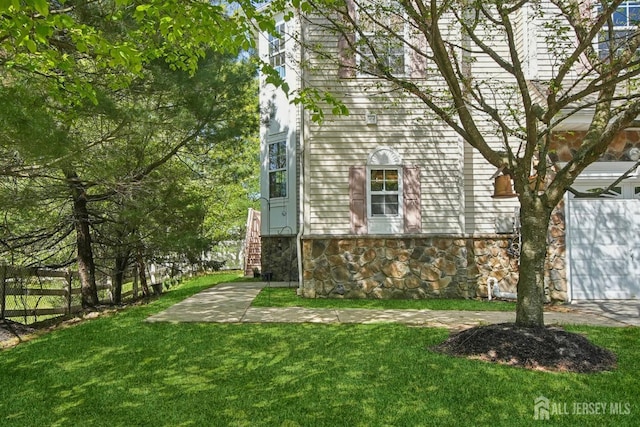 view of property exterior featuring stone siding, a lawn, and stairway