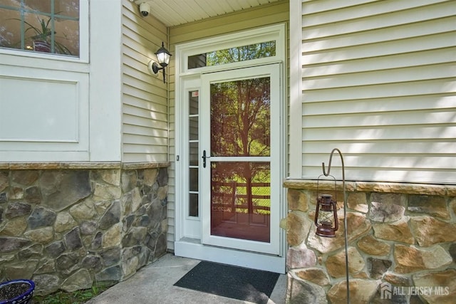 property entrance with stone siding and a surveillance system