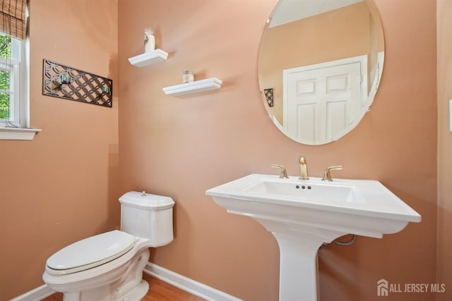 half bathroom featuring toilet and baseboards