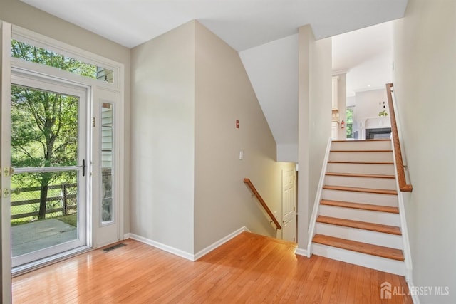 entryway with light wood-type flooring, baseboards, and stairs