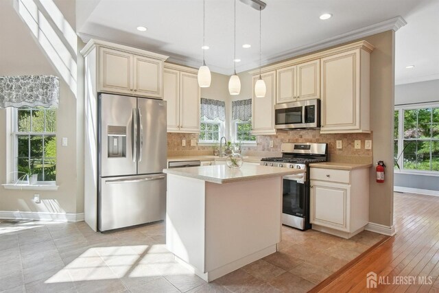 kitchen featuring stainless steel appliances, cream cabinetry, crown molding, light countertops, and recessed lighting