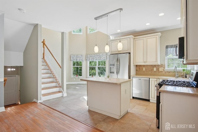kitchen featuring stainless steel appliances, a sink, light countertops, backsplash, and cream cabinetry