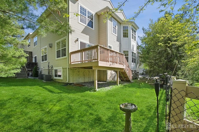 rear view of house with stairs, a lawn, and a deck