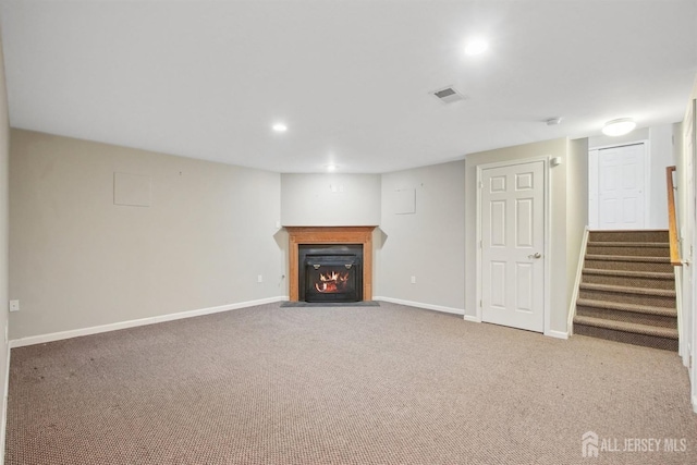 unfurnished living room featuring baseboards, carpet flooring, a fireplace with flush hearth, stairway, and recessed lighting