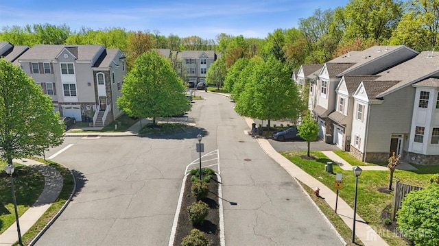 view of asphalt street featuring a residential view, street lights, and sidewalks